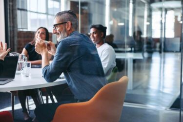 happy-mature-businessman-attending-a-meeting-with-his-team
