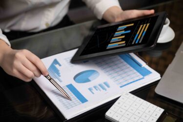 close-up-of-hand-holding-tablet-and-point-pen-at-chart