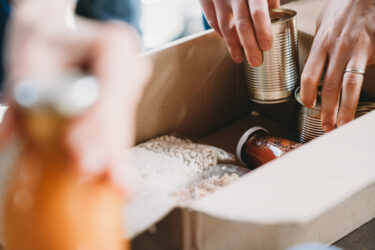 close-up-photo-of-volunteers-preparing-donation-boxes-with-food-at-the-food-and-clothes-bank