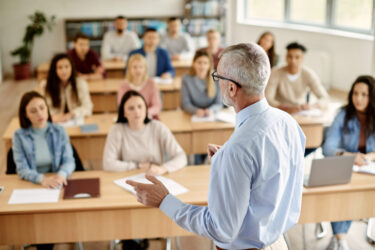 rear-view-of-mature-teacher-talking-to-his-student-during-lecture-at-university-classroom-2