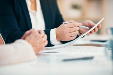 hands-closeup-on-contact-legal-settlement-or-financial-report-while-reading-and-making-notes-lawyer-team-doing-work-and-analyzing-documents-lawyers-looking-through-client-finance-data-together